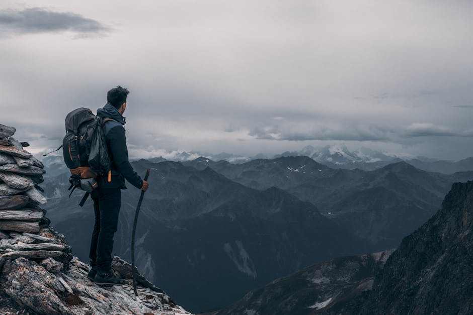 Hiker explores majestic mountain peaks under a moody sky, embodying adventure and exploration.