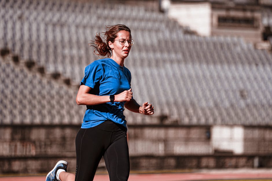 Female athlete running on an outdoor track, showcasing determination and fitness.
