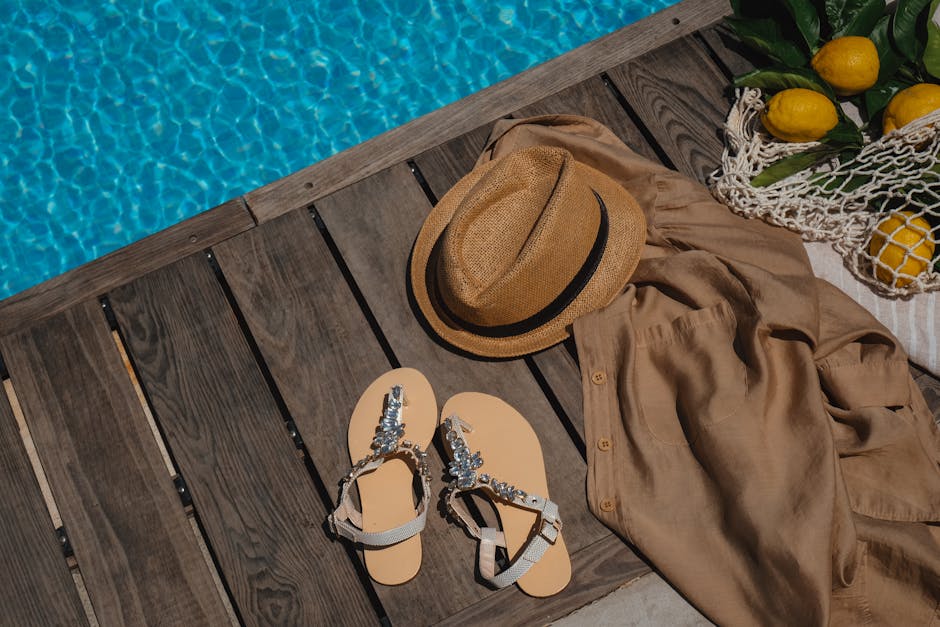 Stylish summer accessories placed by a refreshing poolside setting.