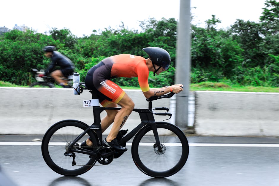 A cyclist in aerodynamic gear racing in wet conditions, showcasing speed and endurance.