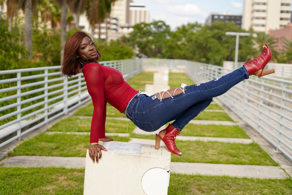Fashion model wearing red top and denim in a modern outdoor setting in Tampa.