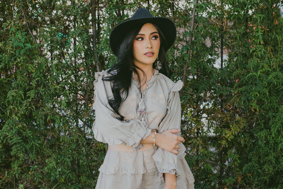 Elegant woman in fall outfit posing outdoors against a green backdrop.