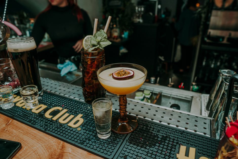 Close-up of cocktails on a bar counter with vibrant decor, showcasing colorful, exotic drinks.