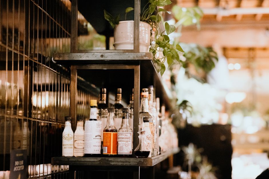 Stylish bar shelf filled with liquor bottles and green plants in a warm indoor setting.