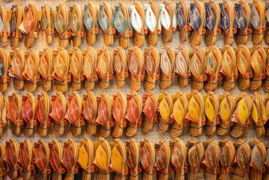 Rows of vibrant traditional leather sandals displayed on a wall.