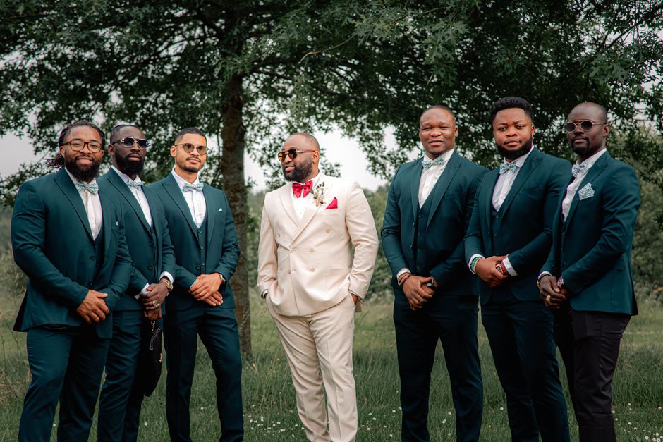A group of dapper groomsmen in suits posing outdoors, exuding confidence and style.