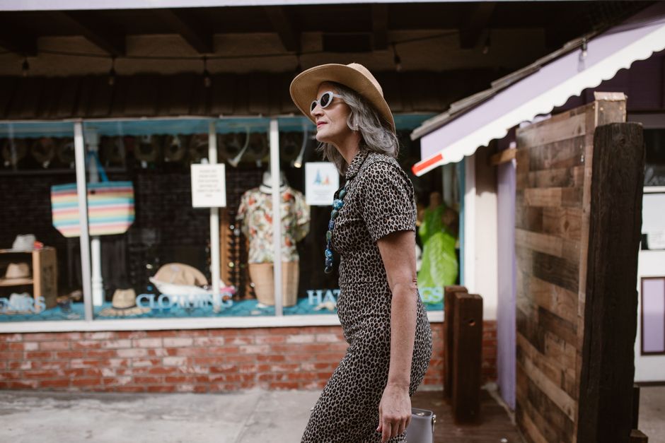 Sophisticated senior woman in leopard print outfit walking confidently through a quaint street.