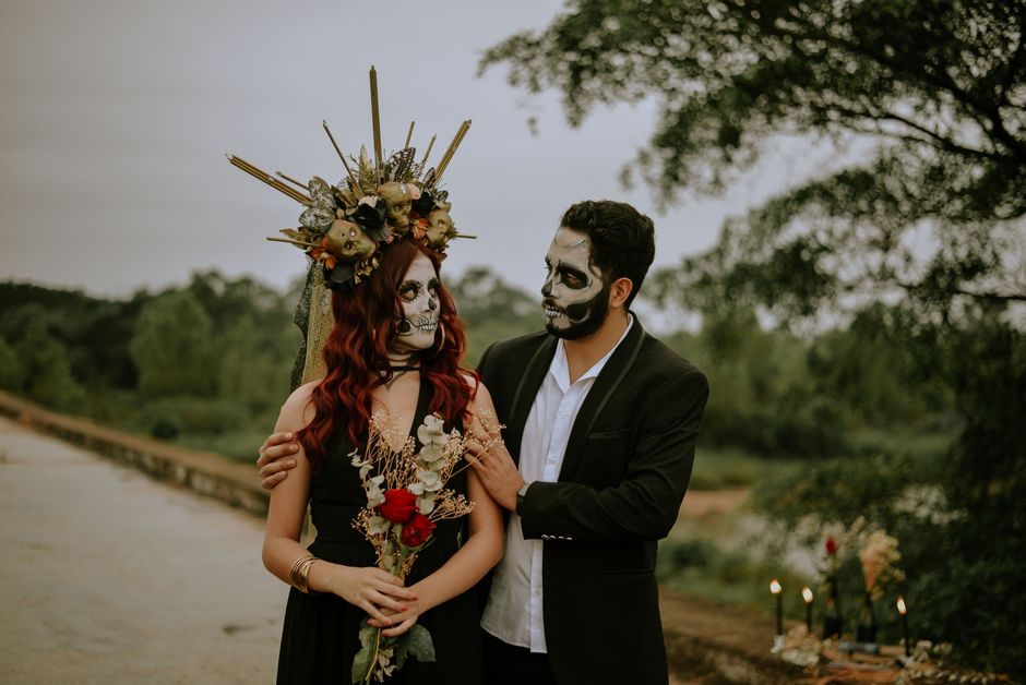 Couple with face paint celebrating Día de los Muertos outdoors.