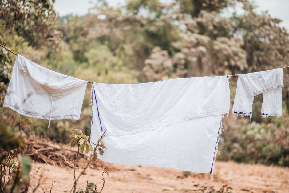 White clothes drying on a clothesline in a rural outdoor setting, surrounded by nature.