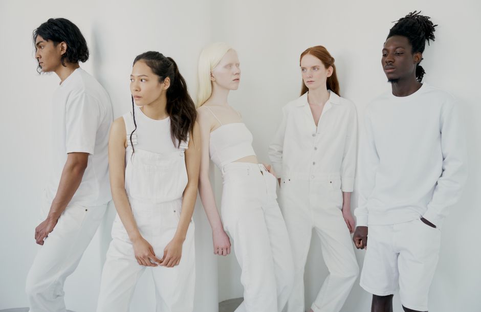 A diverse group of people posing in stylish all-white outfits against a minimalist background.