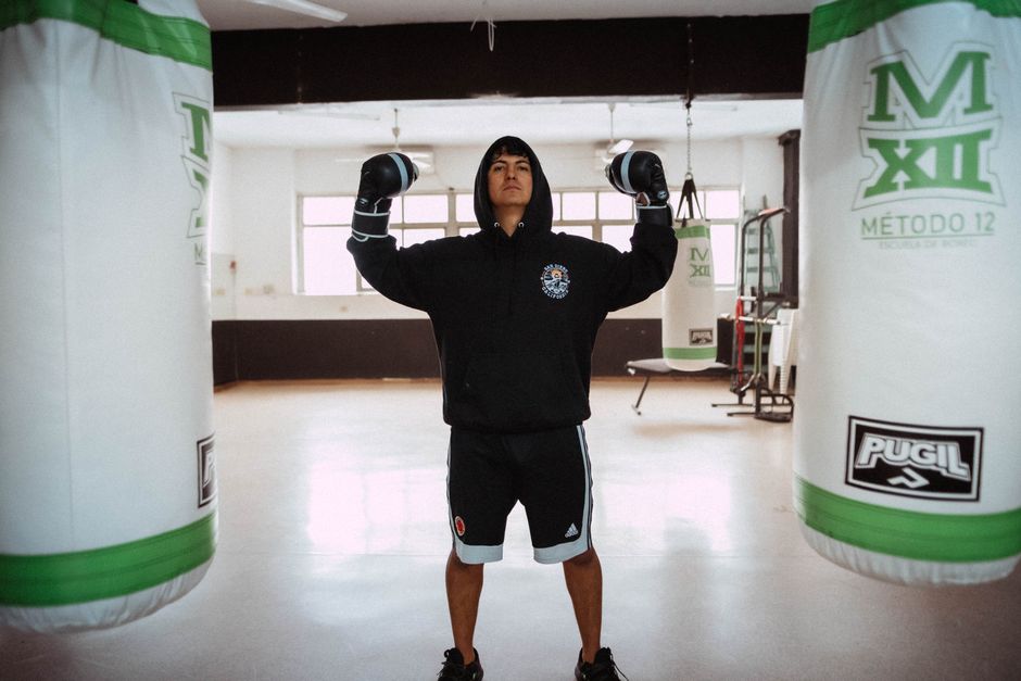 Young boxer training with punching bags indoors in Buenos Aires gym.