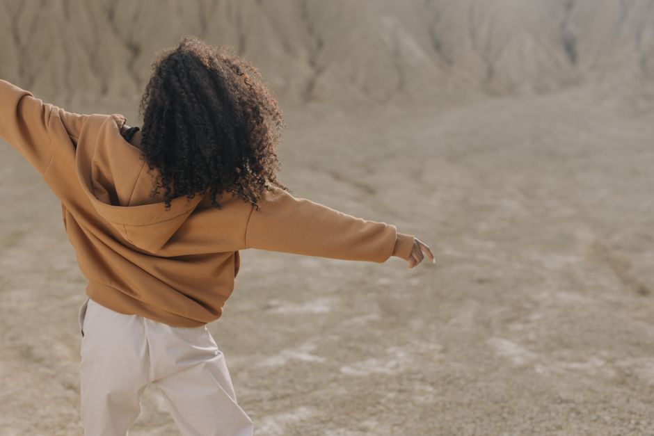 A fashionable woman in a brown hoodie enjoys an open desert landscape.