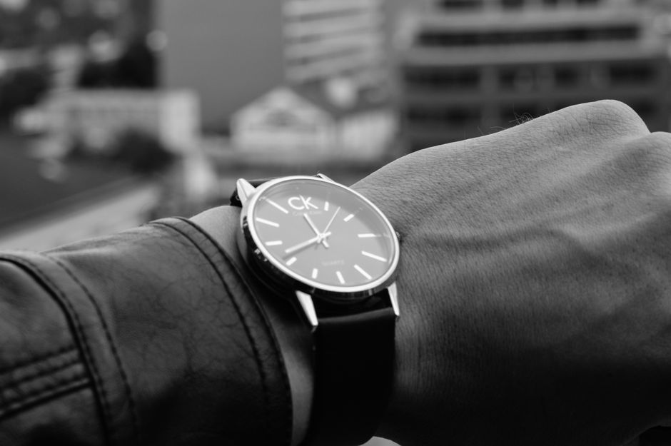 Stylish wristwatch on wrist in an urban outdoor setting, black and white.