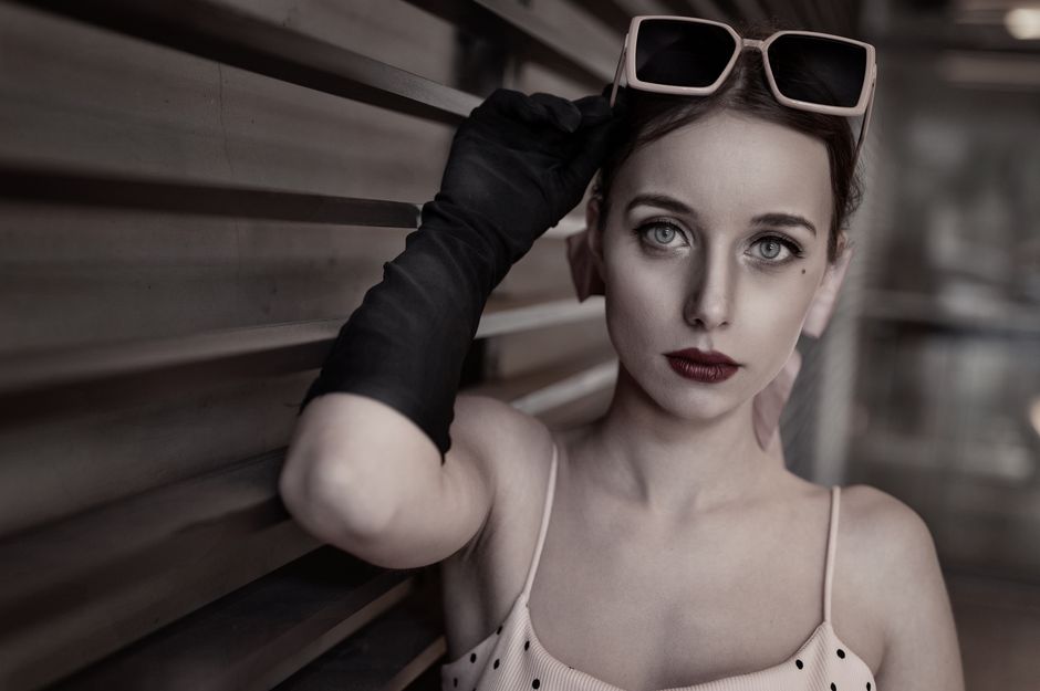 Stylish portrait of a woman in retro sunglasses and gloves, exuding elegance and charm.
