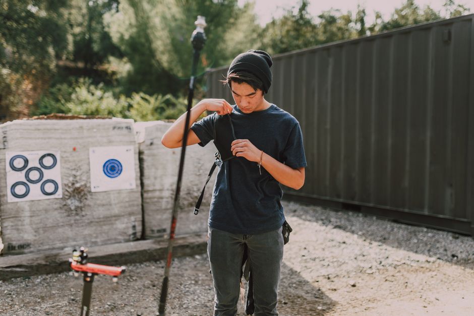 Young man prepares arrows at outdoor archery range, showcasing focus and skill.