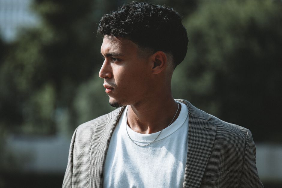 Stylish man in Berlin with urban background, wearing a blazer and white T-shirt.