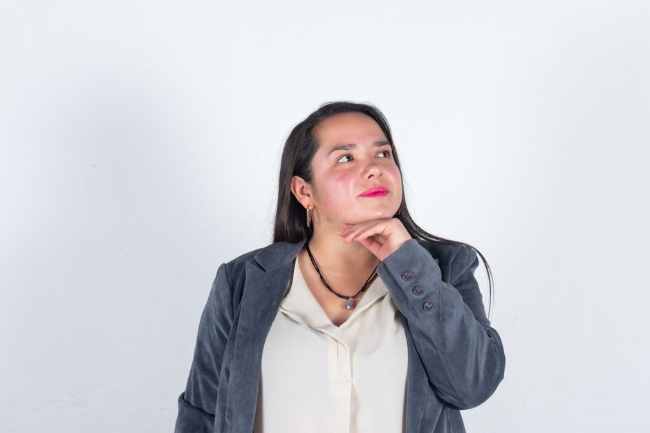 A confident businesswoman in a gray blazer posed thoughtfully against a plain white background.