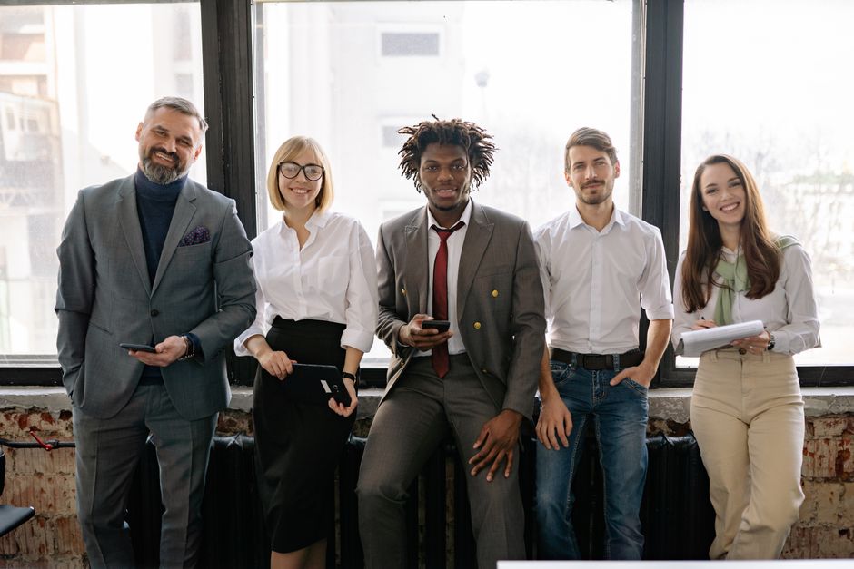 A diverse group of professionals smiling and posing together in a modern office environment.