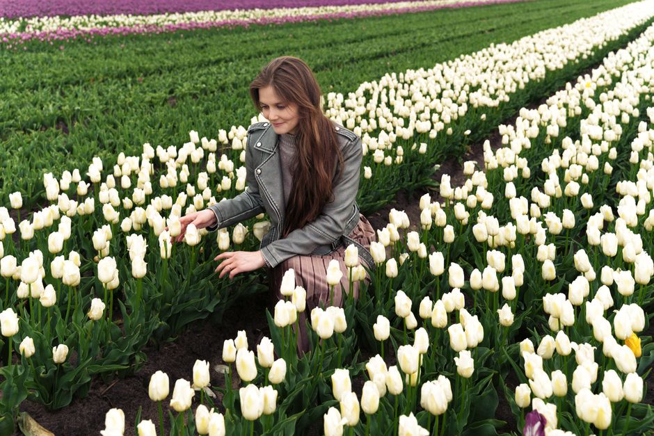 A young woman enjoys blooming white tulips in a scenic field in Тышковичи, Belarus.